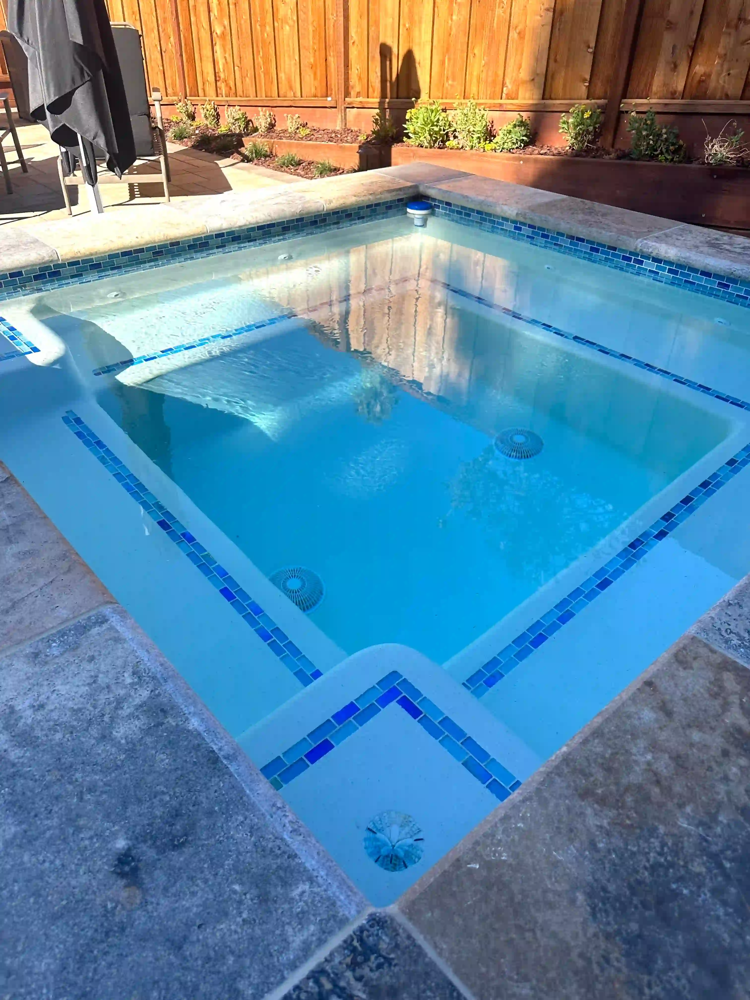 Beautiful backyard pool with integrated spa and stone coping by Legendary Pools Inc.