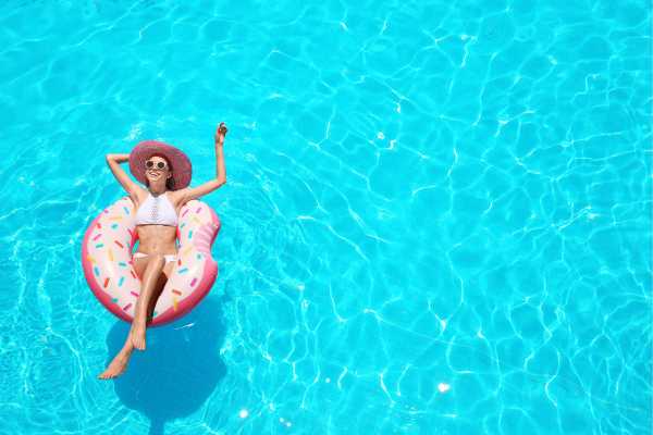 Woman relaxing on a donut-shaped float in a sparkling blue saltwater pool, promoting the enjoyment and benefits of saltwater pool systems. Woman relaxing on a donut-shaped float in a sparkling blue saltwater pool, promoting the enjoyment and benefits of saltwater pool systems.
